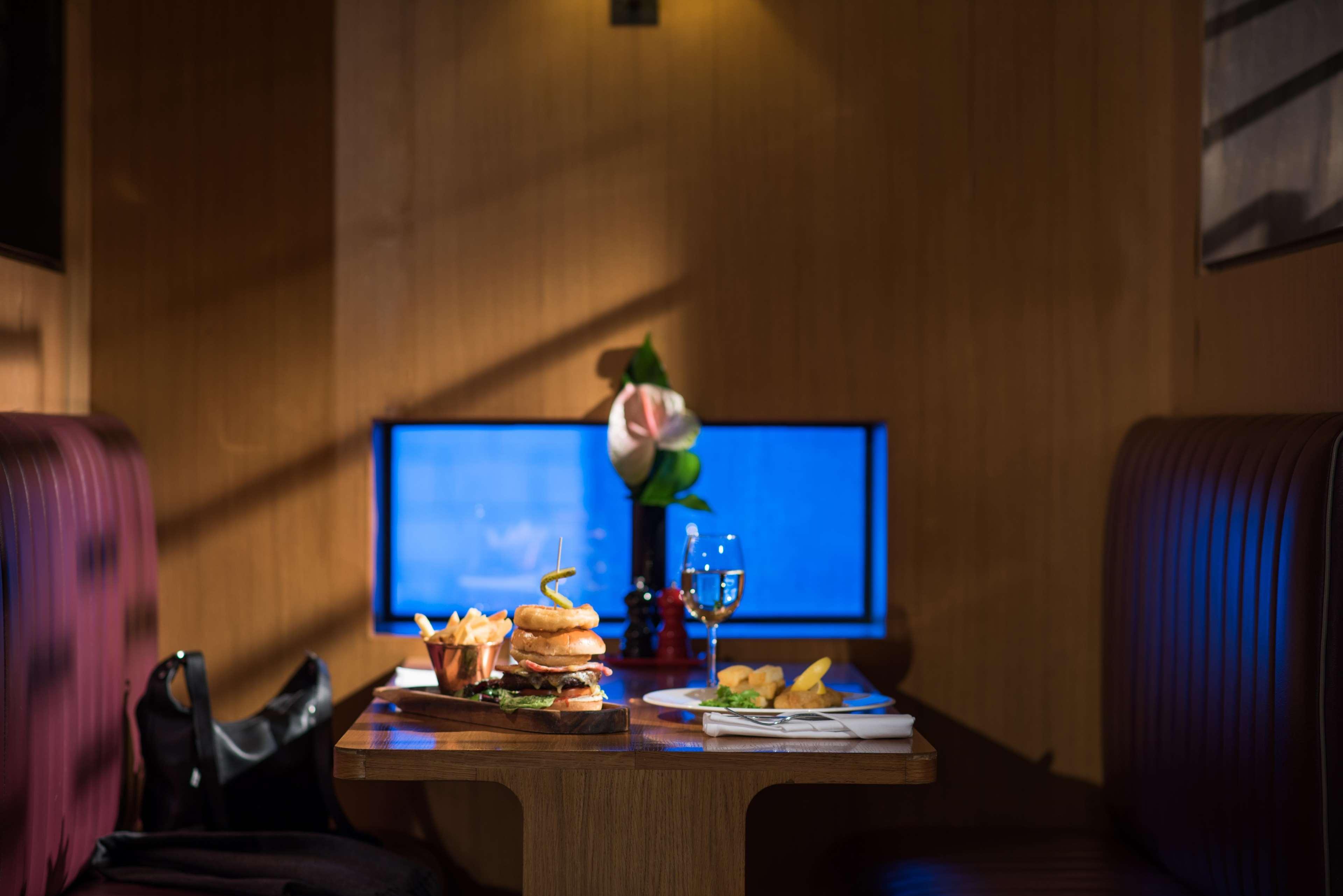 The Fitzwilliam Hotel Belfast Exteriör bild The photo shows a dining table set in a cozy restaurant environment. On the table, there are several food items, including a large burger, some fries, and a small plate with additional items. A glass of wine or another beverage is also present. In th