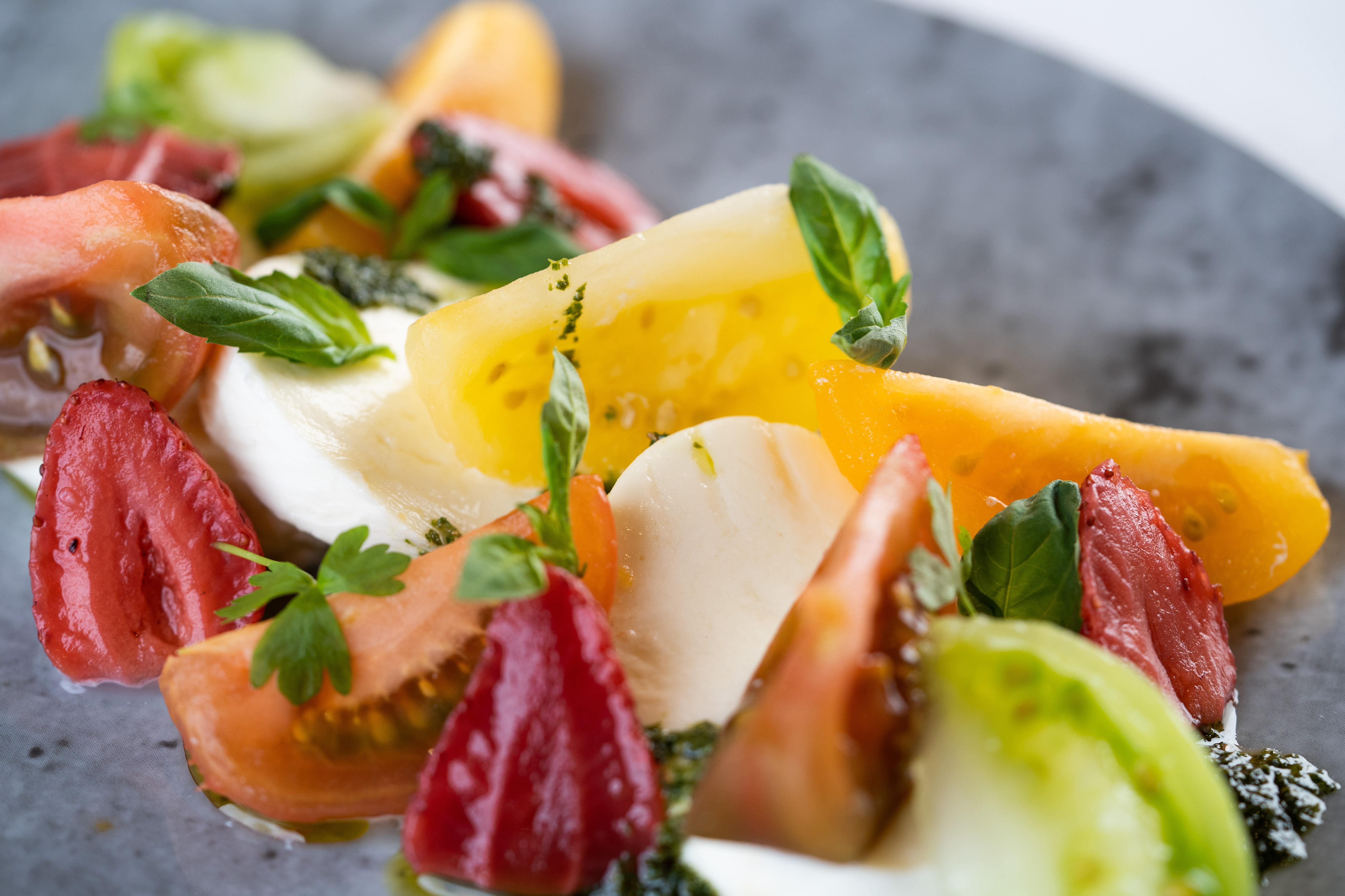 The Fitzwilliam Hotel Belfast Exteriör bild The photo shows a vibrant salad featuring slices of various tomatoes, including red, yellow, and green varieties. The tomatoes are paired with fresh mozzarella cheese and garnished with basil leaves. The dish is presented on a round, dark plate, high
