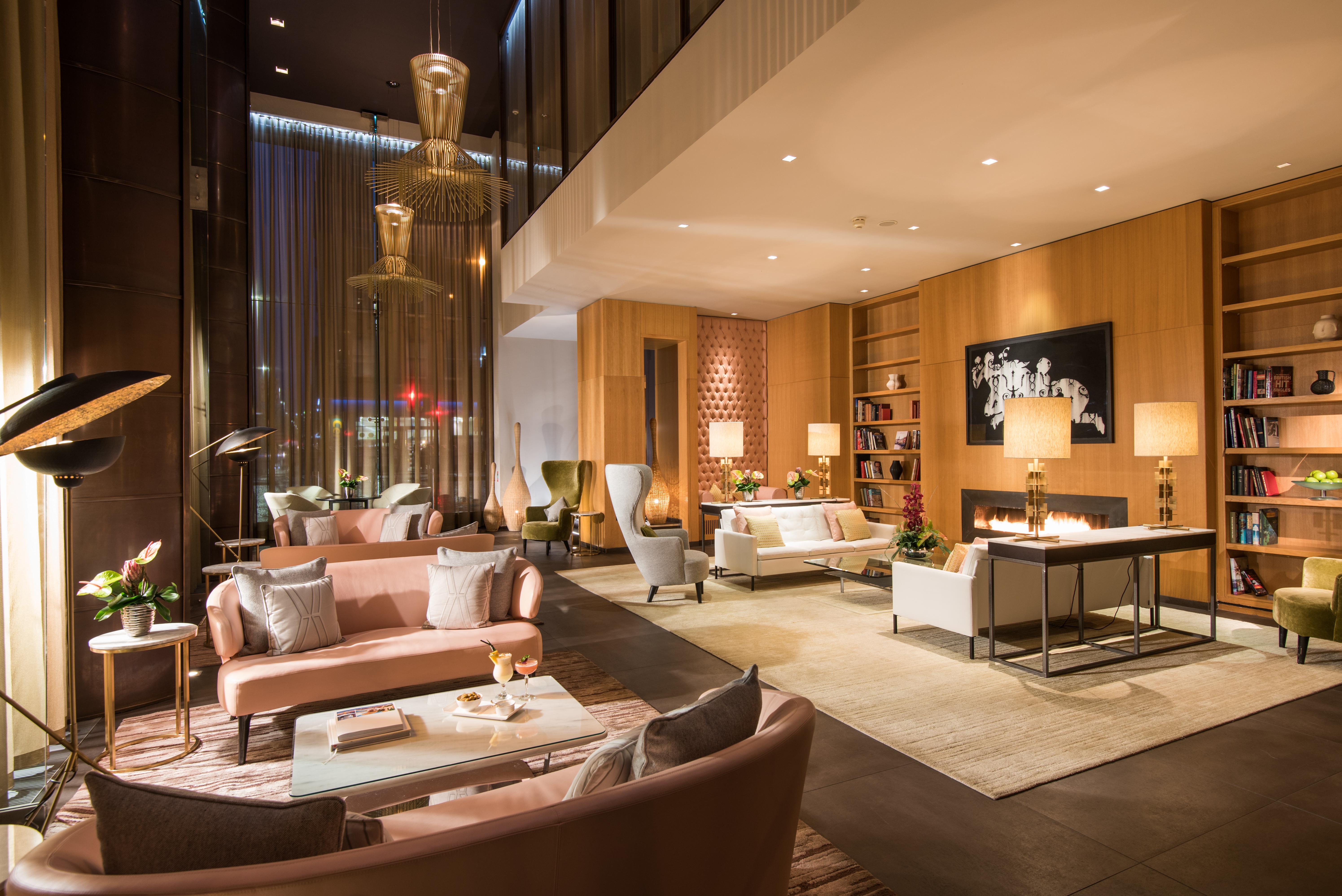 The Fitzwilliam Hotel Belfast Exteriör bild The photo shows a modern and elegant lobby or lounge area. The space features a mix of contemporary and cozy furniture, including light-colored sofas and armchairs arranged around small tables. There are decorative elements like vases with flowers, a